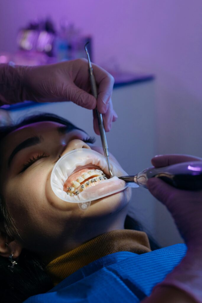 Dentist performing orthodontic procedure on patient with braces in a clinic setting.